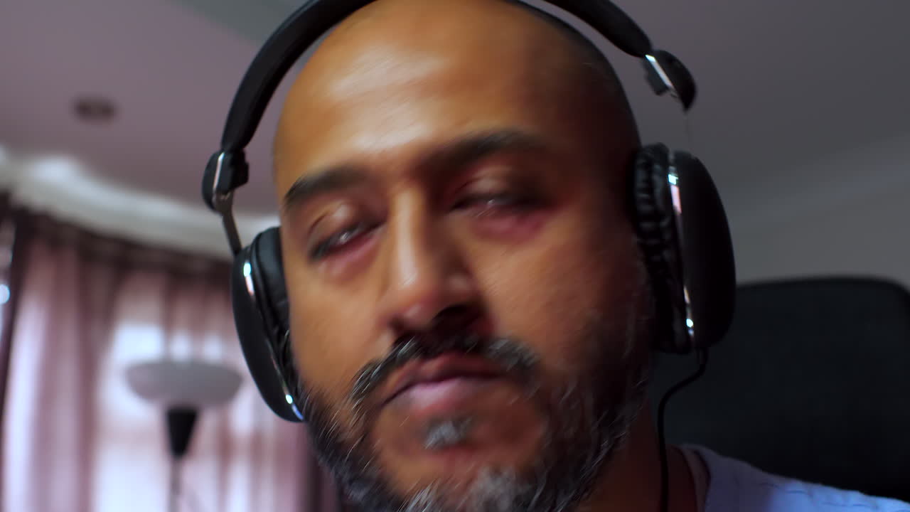 primer plano de un hombre del sur de asia trabajando desde casa, usando auriculares, escuchando música y golpeando la cabeza