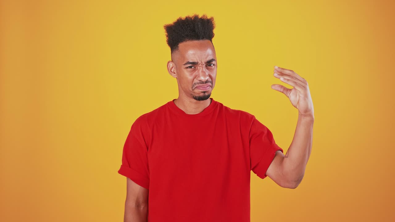hombre afroamericano mostrando bla bla gesto con la mano y sacudiendo la cabeza no, fondo de estudio naranja