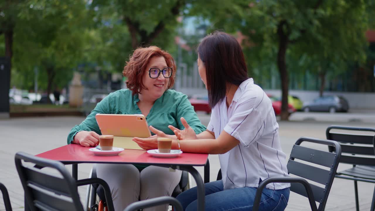 Two women enjoying coffee and conversation at an outdoor cafe