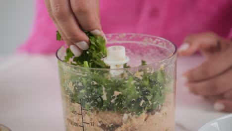 Close-up-adding-ingredients-to-a-food-processor-to-make-crab-cakes