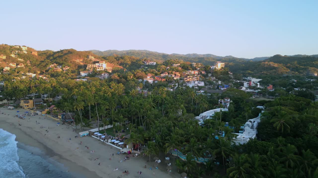 un dron vuela sobre la playa y hacia la ciudad de surf de sayulita mexico durante la puesta de sol
