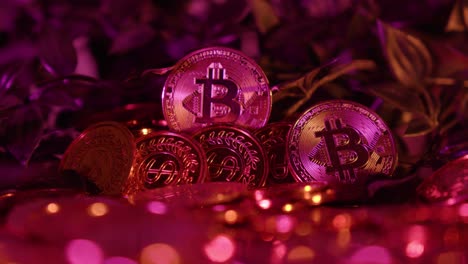 slow establishing shot of gold coins alongside golden bitcoins under red light