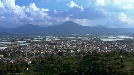 AERIAL:-Tangancicuaro-City,-Mexico,-Forest,-Clouds,-Mountains