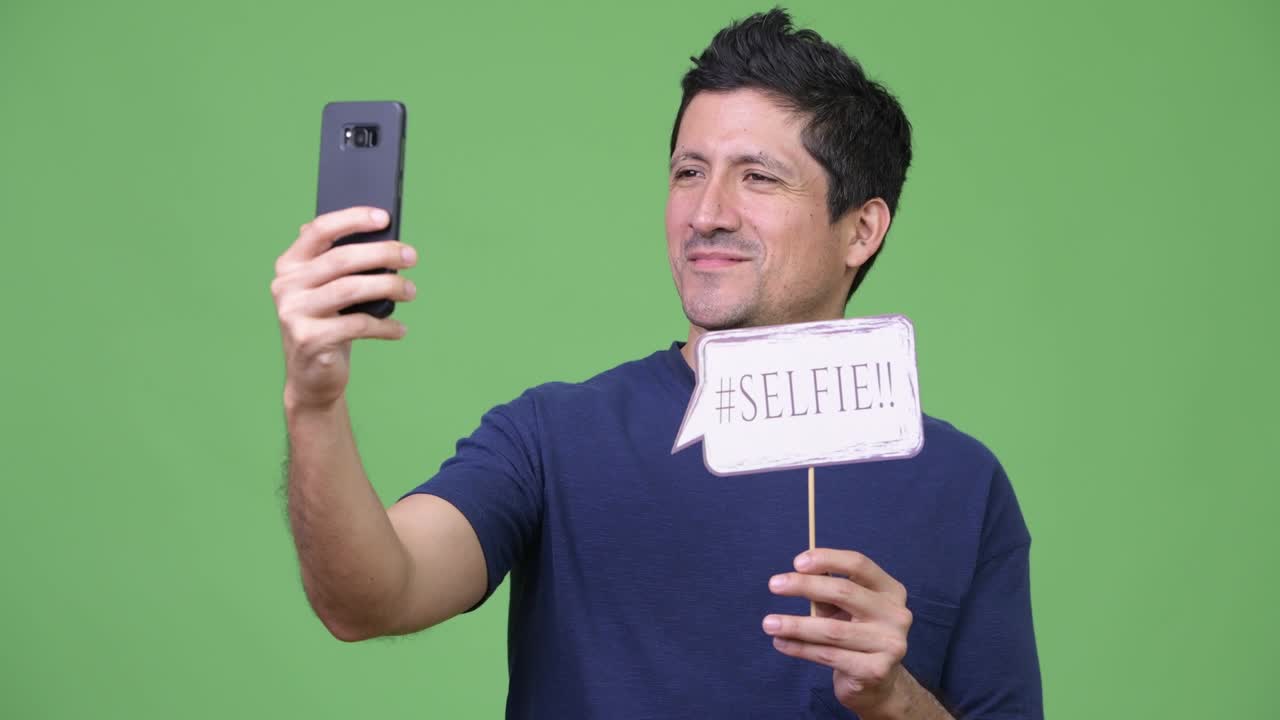 Hispanic man taking selfie with paper sign