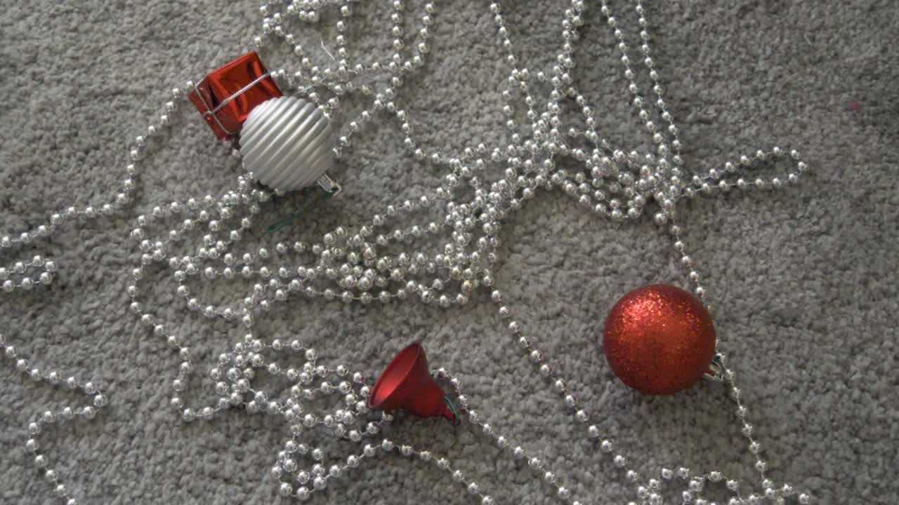 silver bauble falling on the floor and on other christmas decorations