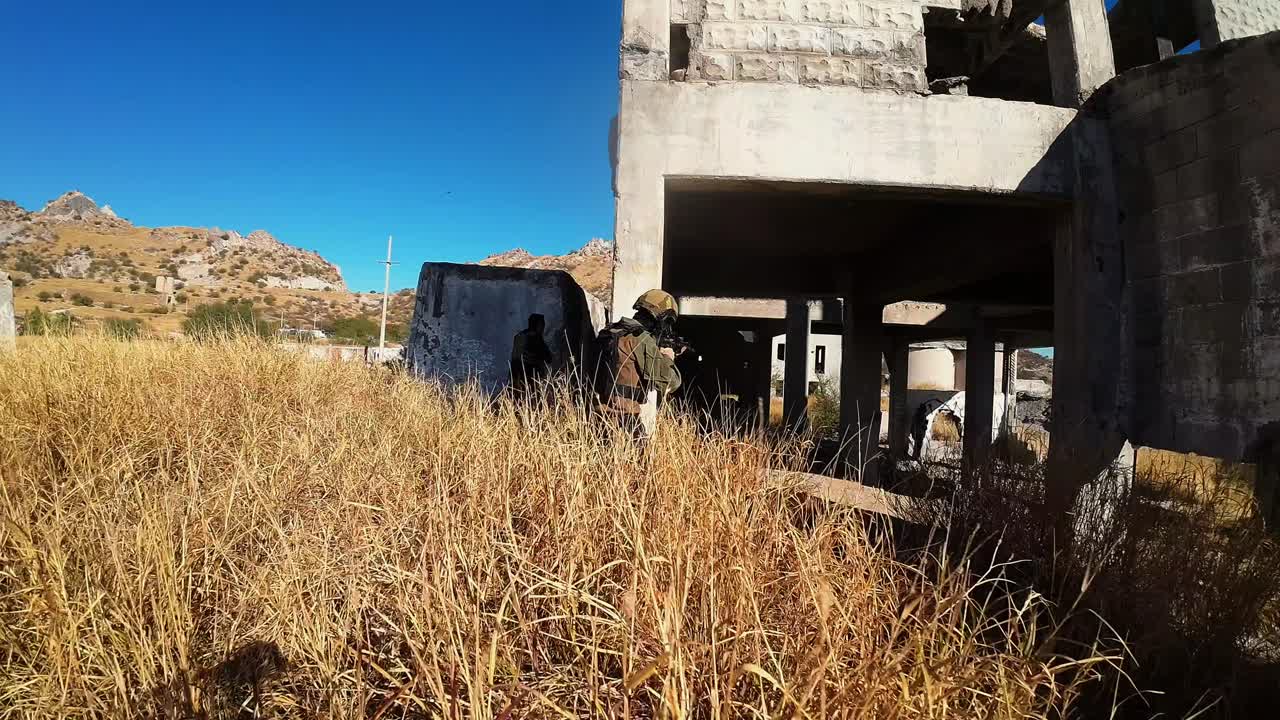 drone vuela sobre un edificio en ruinas donde se practica el deporte del airsoft y varias personas vestidas con equipo militar