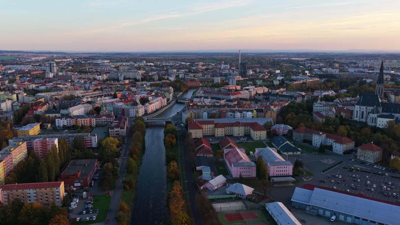 Evening aerial view of Olomouc city with historic buildings, churches and a river reflecting the warm sunset light