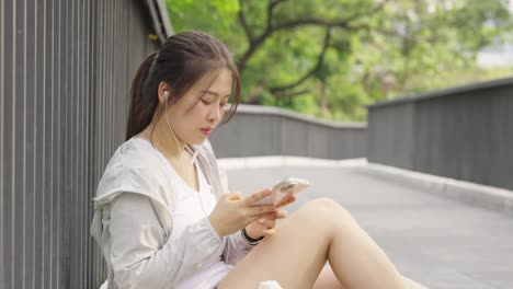 4k asian woman listening to music while jogging at public park in the morning.