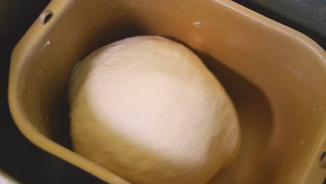 a slow panning shot of dough being kneaded in a bread maker