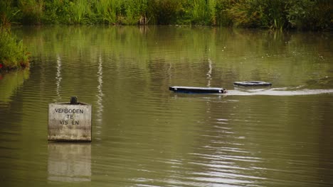 Wide-view-of-a-homemade-radio-controlled-boat-steering-on-a-pond-in-slow-motion