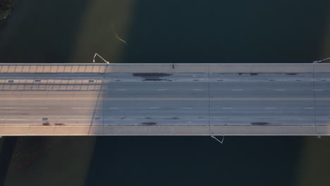 aerial of lonely person crossing bridge then cars begin to drive