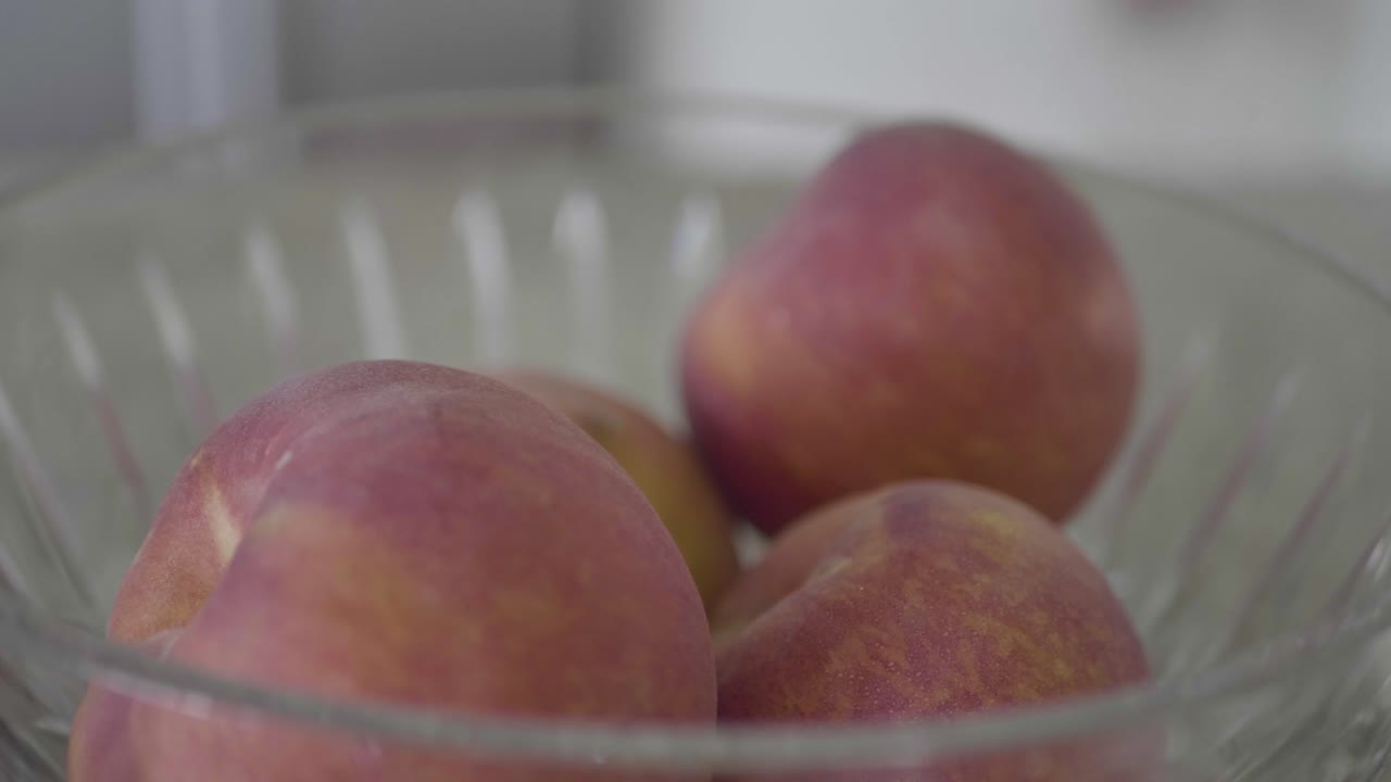 Close-up buah persik segar dalam mangkuk di atas meja dapur.