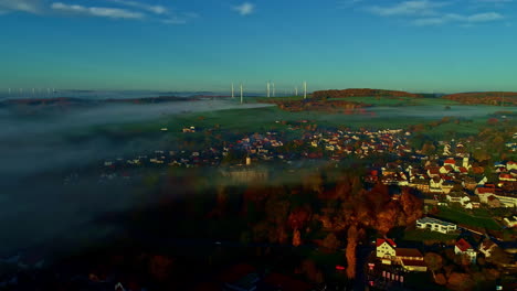 aerial view of a misty village in autumn with wind turbines