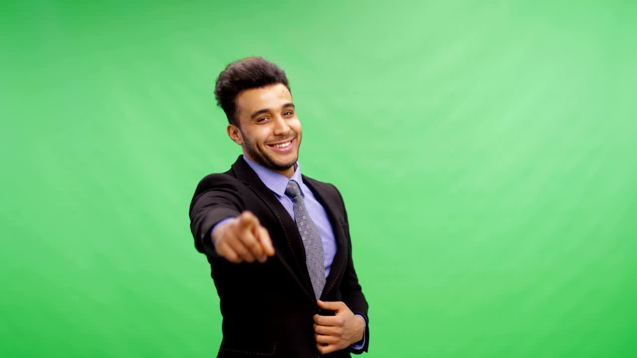 Smilende forretningsmand peger på dig. Glad portræt af ung, munter forretningsmand iført jakkesæt over Chroma Key grøn skærm