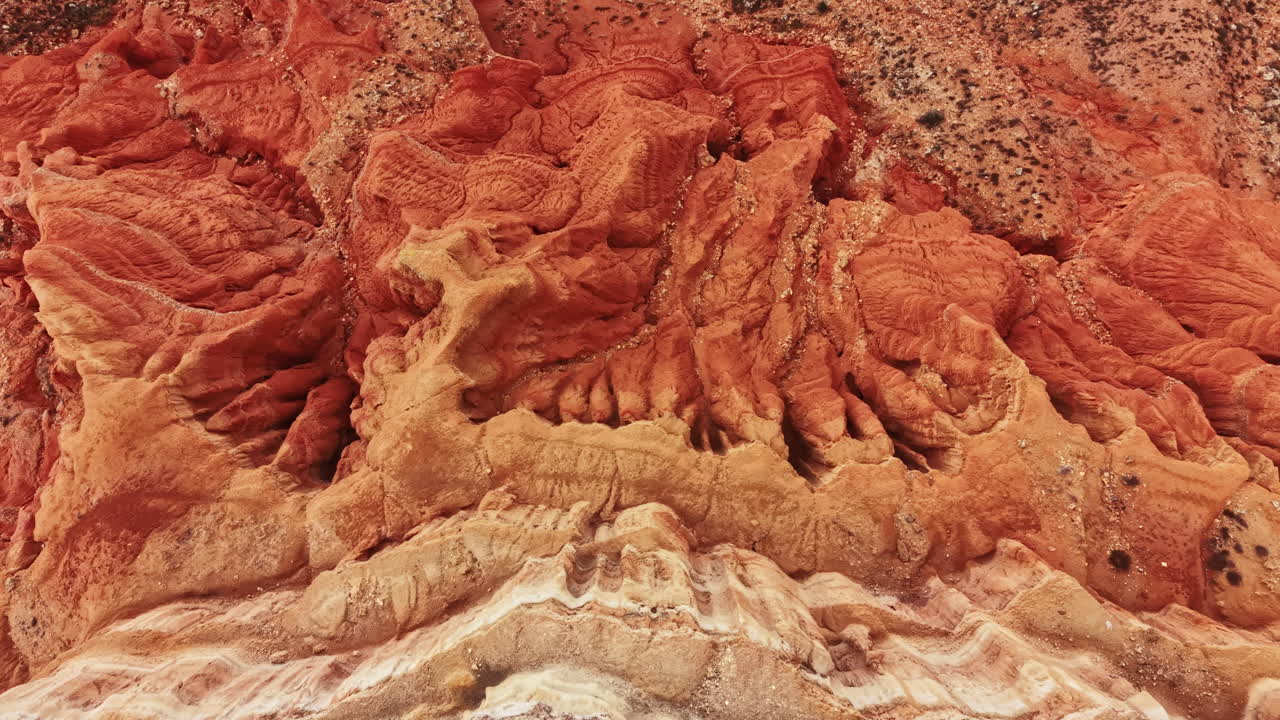 Paesaggio del canyon con strati di formazioni rocciose rosse e marroni sotto la luce intensa del sole a mezzogiorno.