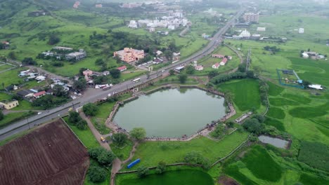 Vista-Aérea-Panorámica-De-Una-Carretera-Muy-Transitada-A-Través-De-Los-Exuberantes-Campos-Agrícolas-Verdes-En-La-Parte-Rural-De-Maharashtra,-India