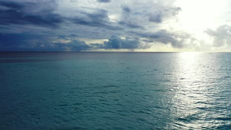 Cielo-Dramático-Sobre-El-Océano-Abierto-Con-Nubes-Oscuras-Y-Sol-Reflejado-En-El-Mar