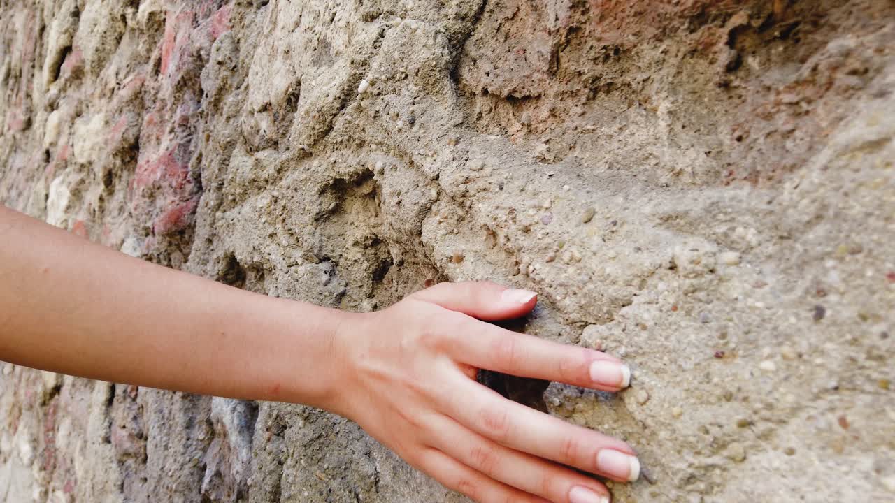 cámara lenta: hermosa joven toca la pared mientras camina por la calle