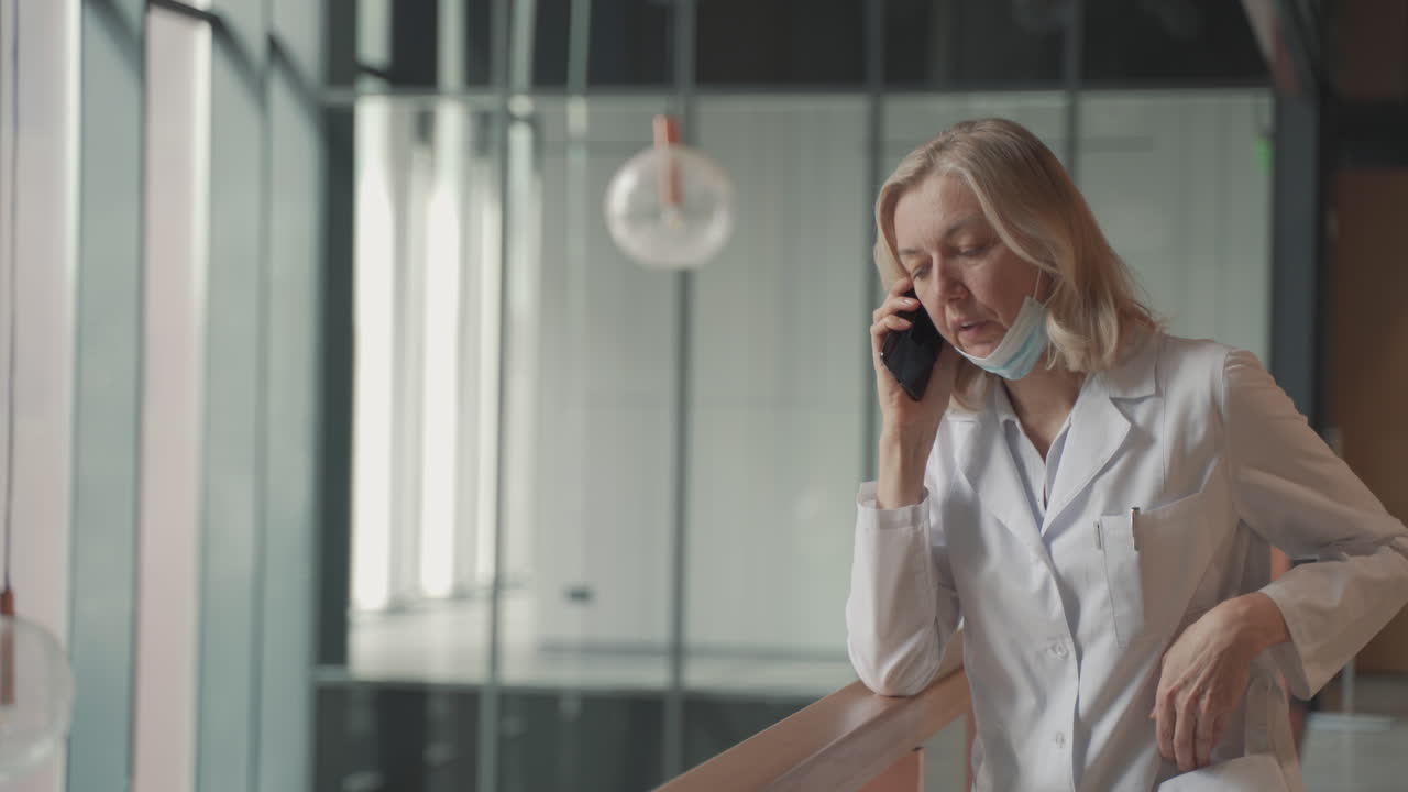 светловолосая женщина-врач средних лет разговаривает по мобильному телефону 1