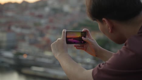 a tourist in the city of porto taking a picture of the sunset in public