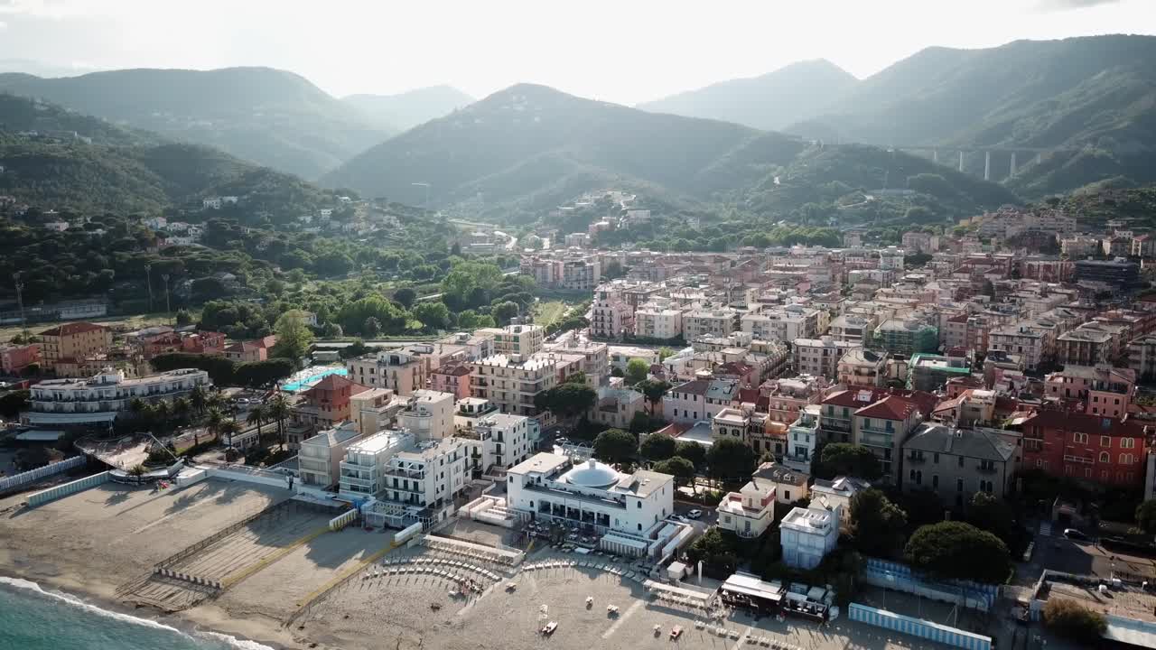 Drone view of a town with mountains behind and a beach. Mediterranean shore during a sunset. Genoa, Italy