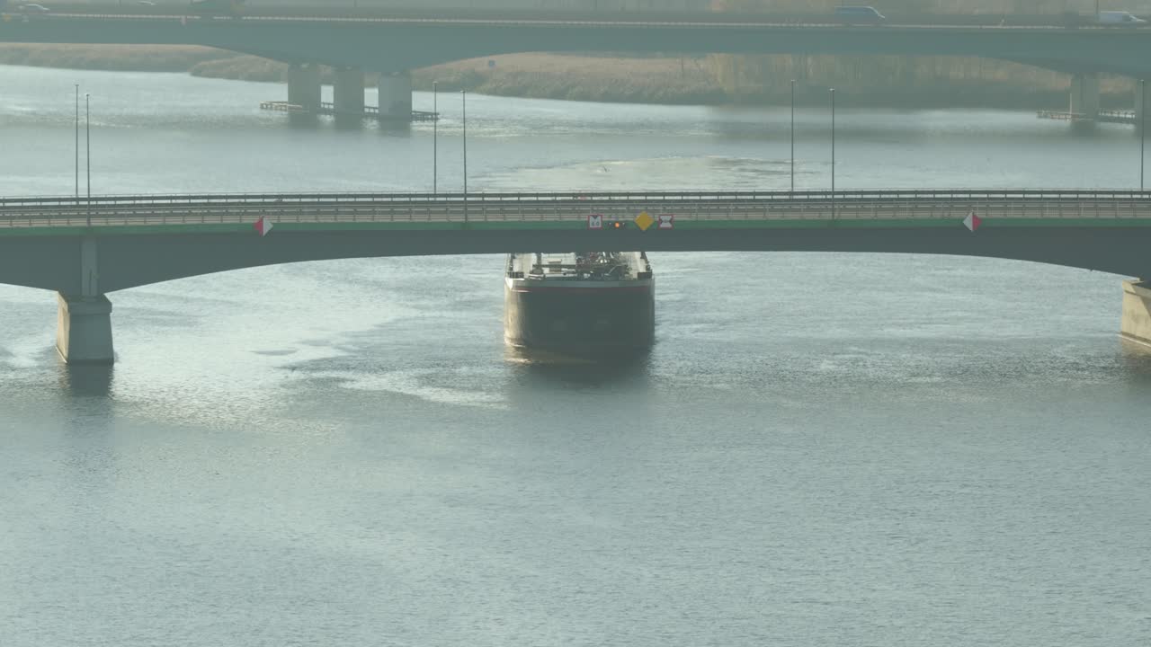 穏やかな朝、平和な海の景色の中を橋の下を航行する原油タンカー。