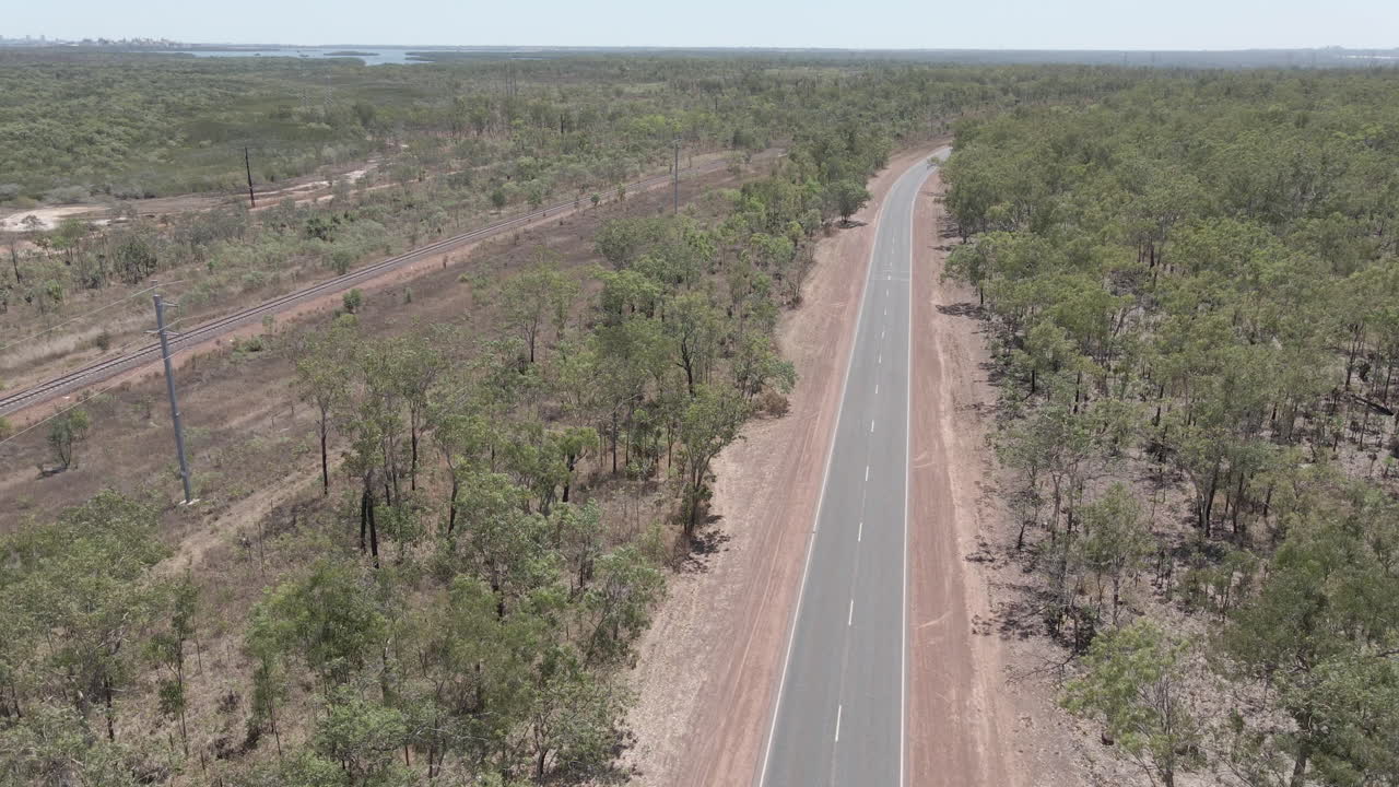 toma aérea de drones en movimiento de la carretera que se traslada a un ferrocarril en el territorio del norte, interior australiano