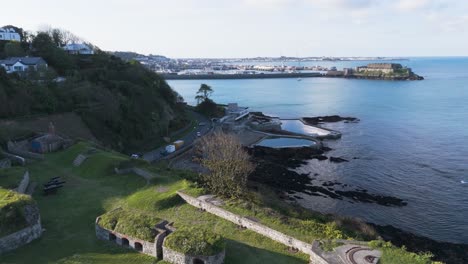 Imágenes-De-Drones-A-Través-De-Las-Piscinas-Para-Bañarse-En-El-Mar-Y-La-Bahía-De-Havelet,-Guernsey,-Desde-Clarence-Battery-Hasta-Castle-Cornet-Y-St-Peter-Port-En-Un-Día-Soleado