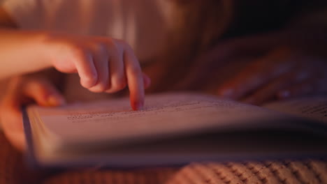 Hand-of-kid-follows-line-with-finger-while-girl-reads-book