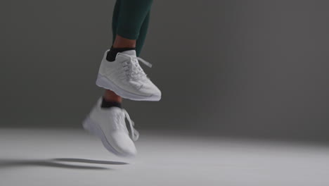 Close-Up-Shot-Of-Feet-Of-Female-Athlete-Wearing-Tracksuit-Training-In-Gym-Fitness-Class-With-Jump-Rope-Or-Skipping-Rope-Against-Plain-Background