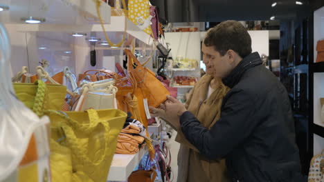 Young-couple-examining-handbags-in-the-store