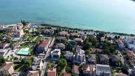 enchanting houses and tranquil shores in peschiera del garda, aerial tilt-up