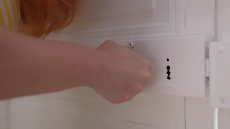 redhead woman trying to open door with old rusty knob, close up