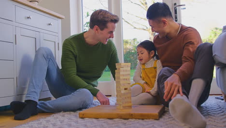 Familia-Con-Dos-Padres-Jugando-Con-Su-Hija-En-Casa-Apilando-Ladrillos-De-Madera-En-La-Torre