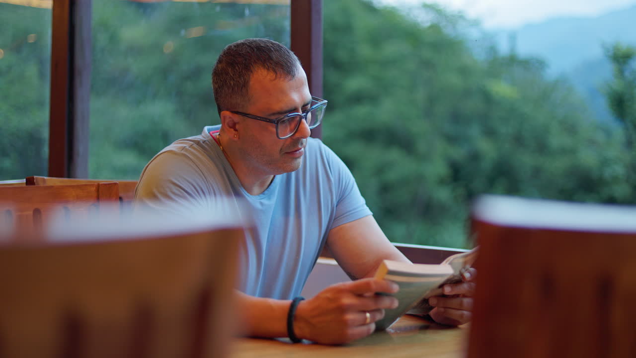 Person sitting at wooden table reading and relaxing in natural countryside