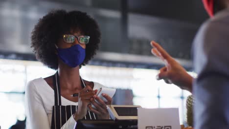 mixed race man giving african american female cafe worker his smartwatch in order to pay