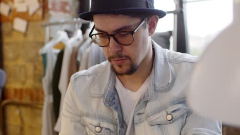 close up of concentrated male fashion designer working in sewing workshop