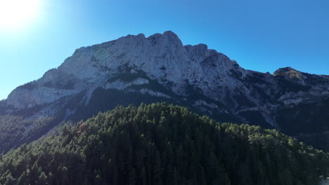 Vista-Aérea-Escalando-Sobre-El-Bosque-De-Pinos-De-Pedraforca-Hacia-El-Majestuoso-Pico-De-La-Montaña-De-Los-Pirineos