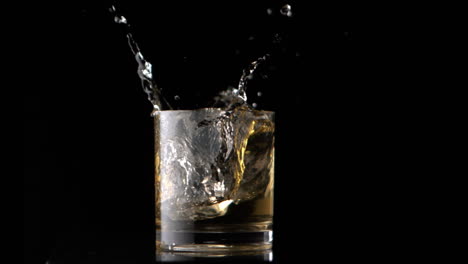 ice cubes falling into whiskey