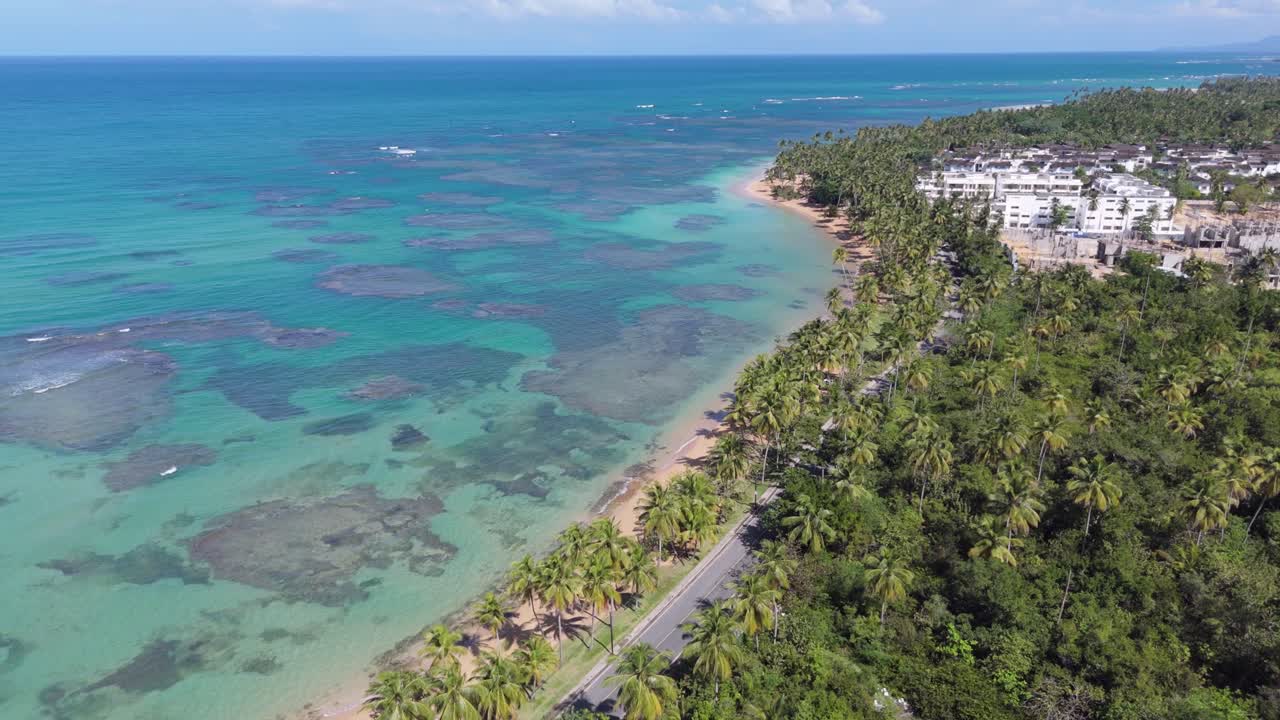 Vista aerea del mare blu, hotel fronte mare e palme in estate a Playa el Portillo a Las Terrenas, Penisola di Samaná, Repubblica Dominicana