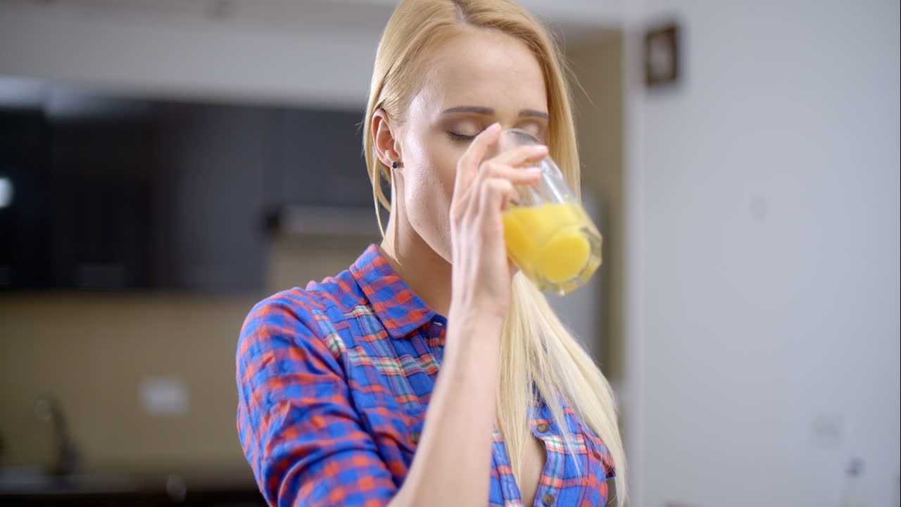 Pretty Blond Woman Drinking Juice in a Glass