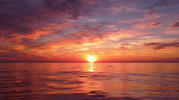 Breathtaking Sunset Over Tranquil Water: An Exquisite Display of Nature's Beauty with Vivid Colors Reflecting on the Calm Ocean Surface