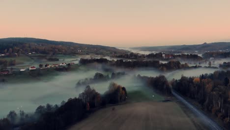 aerial over road cutting through misty farmland near bollebyggd, sweden