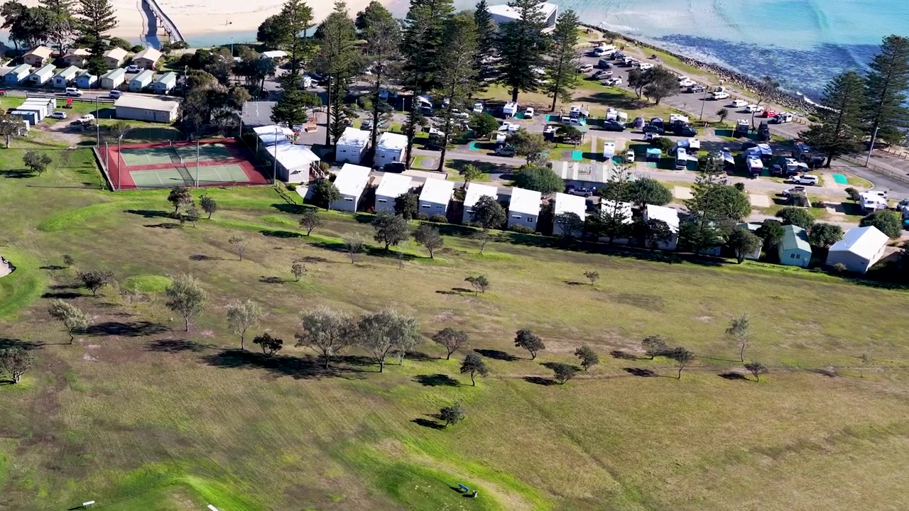 Droneopptak fra høy vinkel over grønne fairways og strandhytter i Crescent Head, Australia