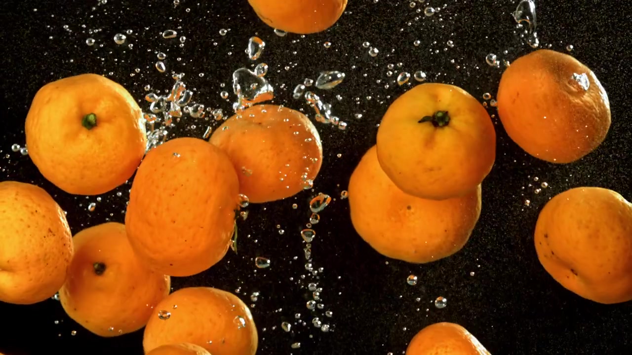 Mandarini freschi che cadono e schizzano nell'acqua su sfondo nero