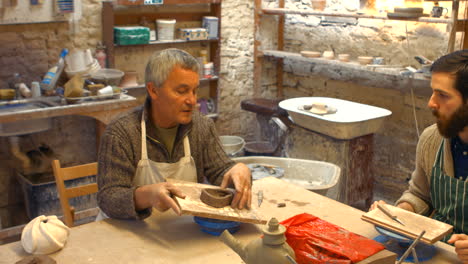 potter teaching his colleague to mold the clay