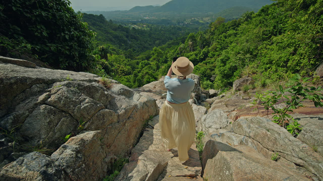 Mulher fotografando uma paisagem tropical com cachoeira