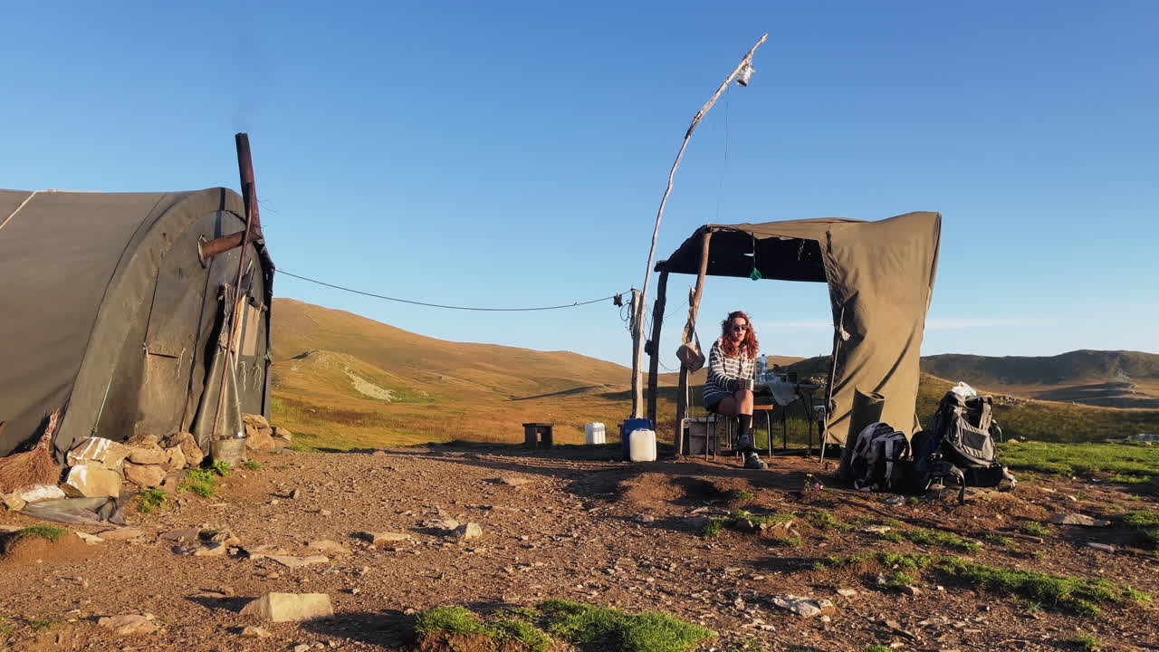 woman sitting in front of tent raising her glass, cheers, rural tent cover image