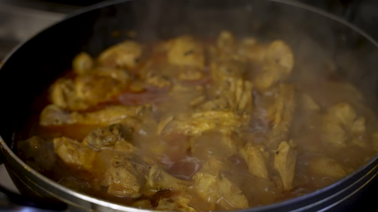 vista de cerca del burbujeante curry de pollo a fuego lento en una olla con vapor subiendo