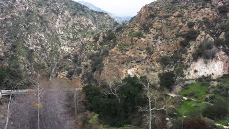 aerial push in shot of the rocky rugged mountain landscape over eaton canyon falls trail and chuck ballard memorial bridge in angeles national forest